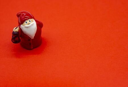 Ceramic figure of Santa Claus on a bright red background. Copy space, flat layの写真素材