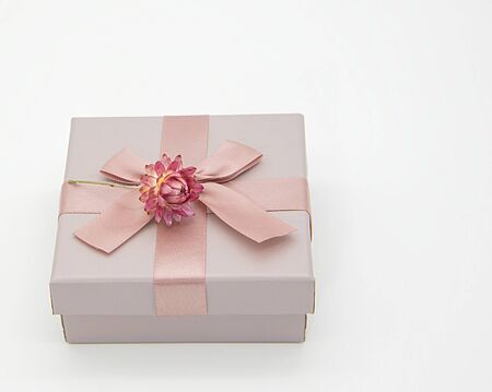 A gift box for jewelry and dried flower on a light background.