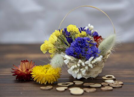 Basket with dried flowers and wooden hearts around on a wooden table top.の写真素材