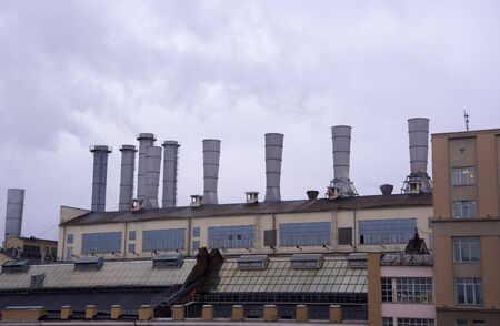 Pipes of the enterprise with steam coming out of them against the dark gray sky.の写真素材