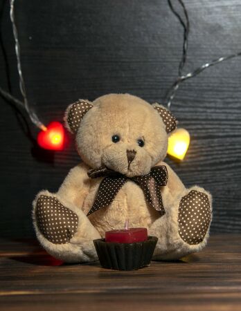 Soft toy bear and garland with hearts on a dark wooden background.の写真素材