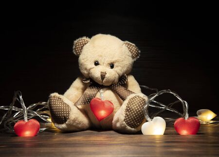 Soft toy bear and garland with hearts on a dark wooden background.の写真素材