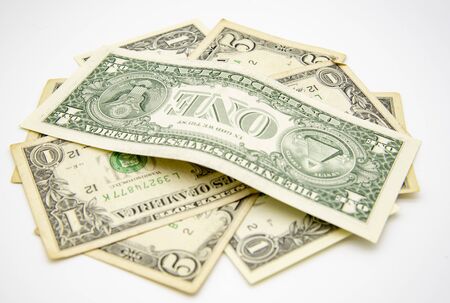 Several old, small-denomination dollar bills are stacked on a light background.の写真素材