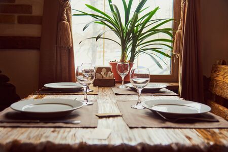 Textured wooden table by the window, set for dinner in the house. Selective focus.の写真素材