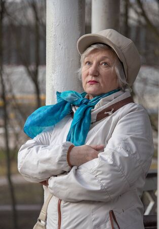 An elegant elderly woman in a fashionable beret is leaning against a column in a public Park.の写真素材
