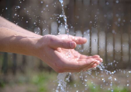 male hands under a stream of water .の写真素材