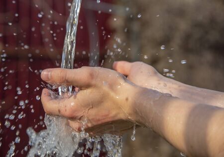 male hands under a stream of water .の写真素材