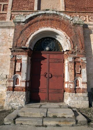 The photo shows an Old brick arch that frames the entrance to the temple, and large iron doors.の写真素材