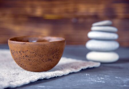 A bowl of tea on a linen towel, with a pyramid of stones in the background.の写真素材