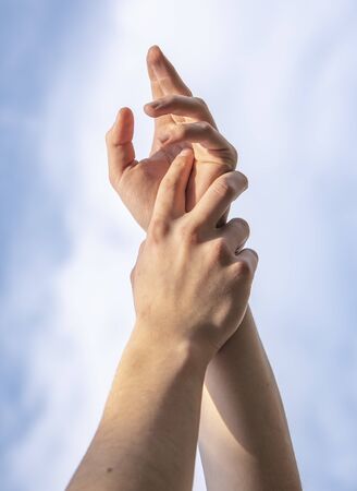 Strong male hands against a blue cloudy sky.の写真素材