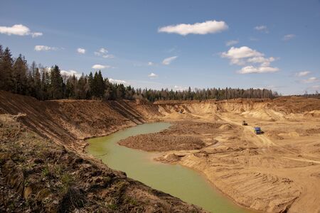 Sand deep quarry under a blue cloudy sky. Construction industry, mining.の写真素材