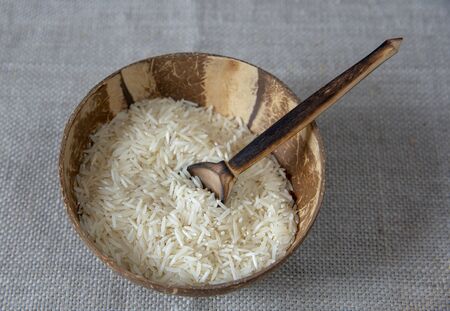 Coconut bowl with raw rice on a linen cloth. Healthy food and environmentally friendly materials.の写真素材