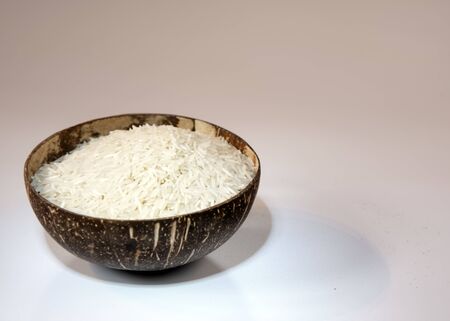Coconut bowl with dry rice on a light background. Healthy food, environmentally friendly materials.の写真素材