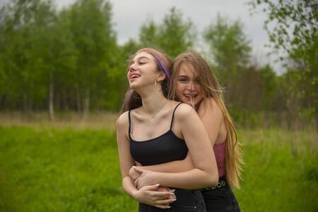 Two teenage girls with long hair on a walk hug each other. The concept of friendship, same-sex relationships.の写真素材