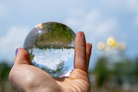 The glass ball lies in the woman's palm. The ball reflects the monastery and nature.