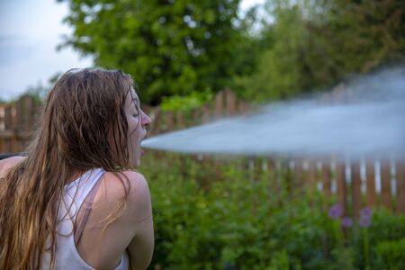 A girl with an open mouth. From the mouth as if a powerful jet of water flies out. Summer...