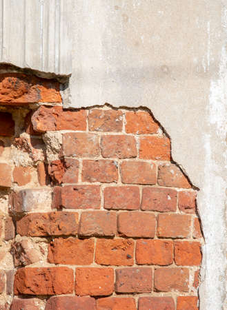 A fragment of an old brick wall with gray paint peeling off.の写真素材