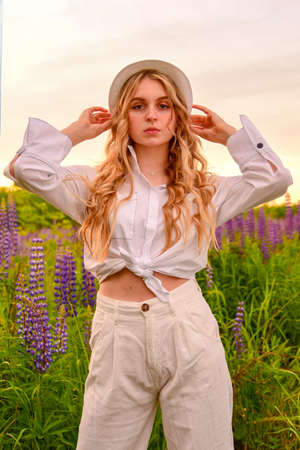 A girl with long blond hair, poses against a background of blooming lupines.の写真素材