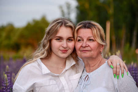 A grandmother and a teenage granddaughter pose in lupine fields.