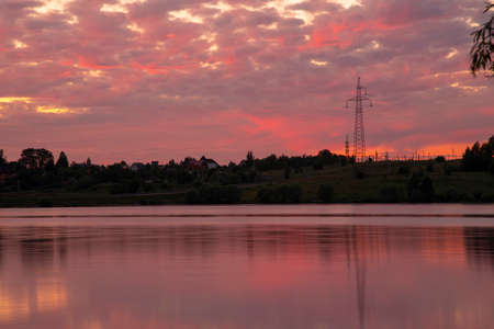 A bright red sunset over the lake is reflected in the water.の写真素材