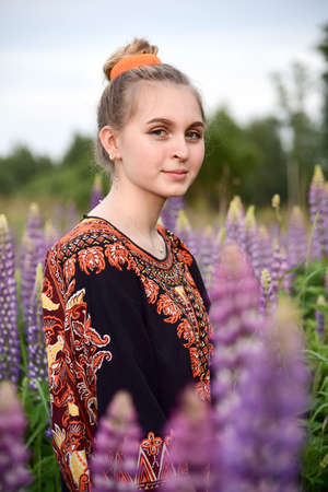 A beautiful girl with blonde hair poses in a Lupin field.の写真素材