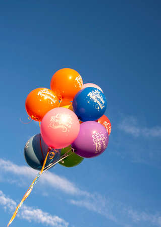 Bright balloons with the inscription in Russian Happy Birthday on the background of a bright blue sky. Festive background.の写真素材