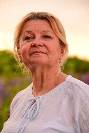 Portrait of an elderly woman against the  lupine fieldの写真素材