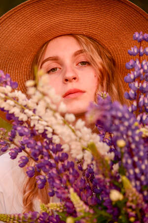 A large portrait of a young girl with light hair in a straw hat surrounded by bright flowers.の写真素材