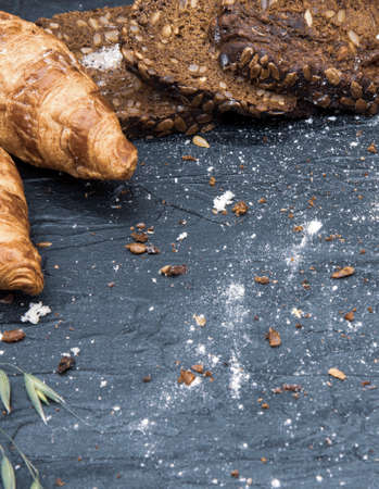 Frame made of different bread and white flour on a dark slate background.Copy space for text, design, and advertising of bakery products.の写真素材