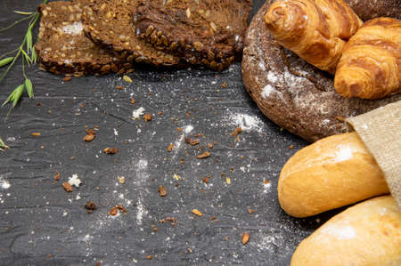 Frame made of different bread and white flour on a dark slate background.Copy space for text, design, and advertising of bakery products.の写真素材