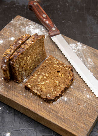A few pieces of grain bread and a knife lie on a rough cutting Board, dusted with flour.の写真素材