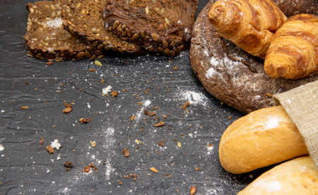 Frame made of different bread and white flour on a dark slate background.Copy space for text, design, and advertising of bakery products.の写真素材