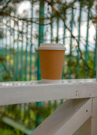 A single-use cardboard glass stands on a wooden crossbar.の写真素材