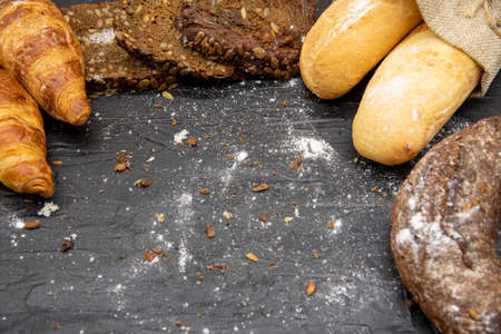 Frame made of different bread and white flour on a dark slate background.の写真素材
