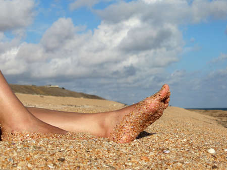 Womens tanned legs on the sea sand .の写真素材