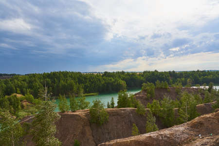 Green lake among the sand hills on the textured background of the cloudy sky.の写真素材