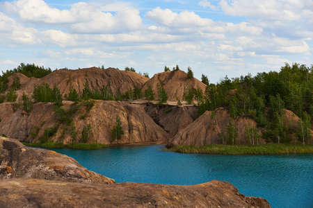 Bright summer landscape. Blue lake among the sand hills on the textured background of the cloudy...