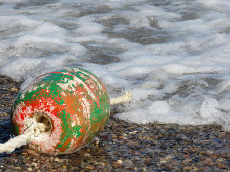One old battered buoy on a rope in the sea waves.の写真素材