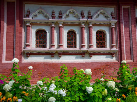 Elegant bright flower bed against the background of the brick wall of an old monastery. Landscape design.の写真素材