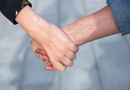 The hand of a young girl holds the wrinkled hand of an old woman.の写真素材