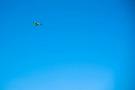 A small green plane flies against a bright blue cloudless sky. Copy space for text.の写真素材