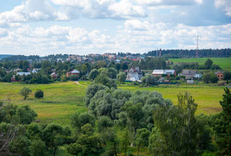 Summer landscape. View from the hill to the fields, forest and village under a cloudy sky.の写真素材