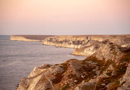 Gentle sunset over the sea and rocky relief coast. Summer evening seascape.の写真素材