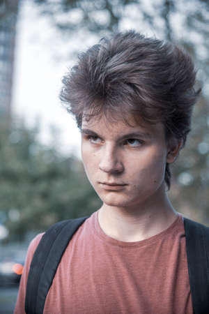 Portrait of a serious boy, a 17-year-old teenager in a red t-shirt with thick hair.の写真素材