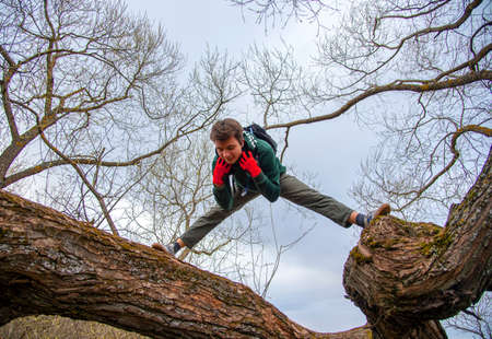 Russia, Moscow region, may 2020. A young man in sports clothes stands on a tree trunk against a cloudy sky.のeditorial素材