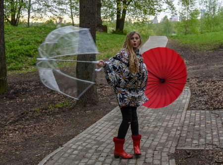 A girl with blonde hair with two umbrellas is spinning in an alley in the Park.の写真素材