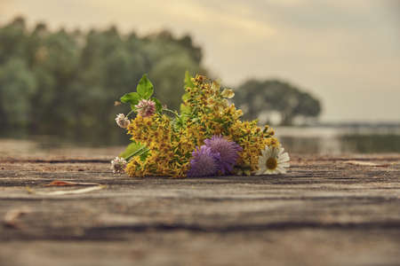 A bouquet of wild flowers lies on a wooden bridge on a blurry background .の写真素材