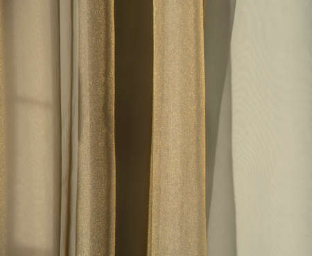 Abstract background. A gold curtain hanging from a window against the wall. Copy space for text, design.の写真素材