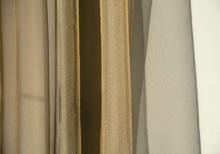 Abstract background. A gold curtain hanging from a window against the wall. Copy space for text, design.の写真素材