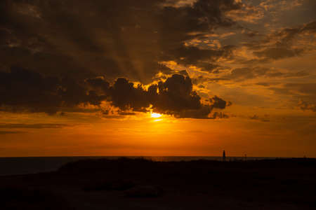 Dark dramatic sunset over the earth. The sun's rays break through the clouds.の写真素材